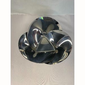 Op de afbeelding: Een zilveren metalen kom met een uniek, driedimensionaal, bloemvormig ontwerp.