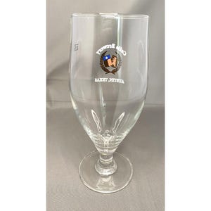 May include: A clear glass beer glass with a stem and a round base. The glass has a logo with the text "Cold Bruch" and "Austin, Texas" in white. The logo features a shield with a star and a flag.