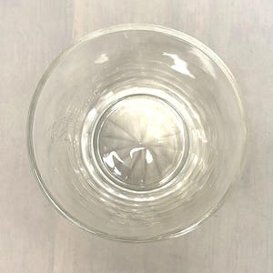 Puede incluir: Un vaso transparente y vac&iacute;o con un borde ancho, visto desde arriba. El vaso tiene una base interior ligeramente texturizada y un cuerpo liso y transparente. El vaso es probablemente para beber.
