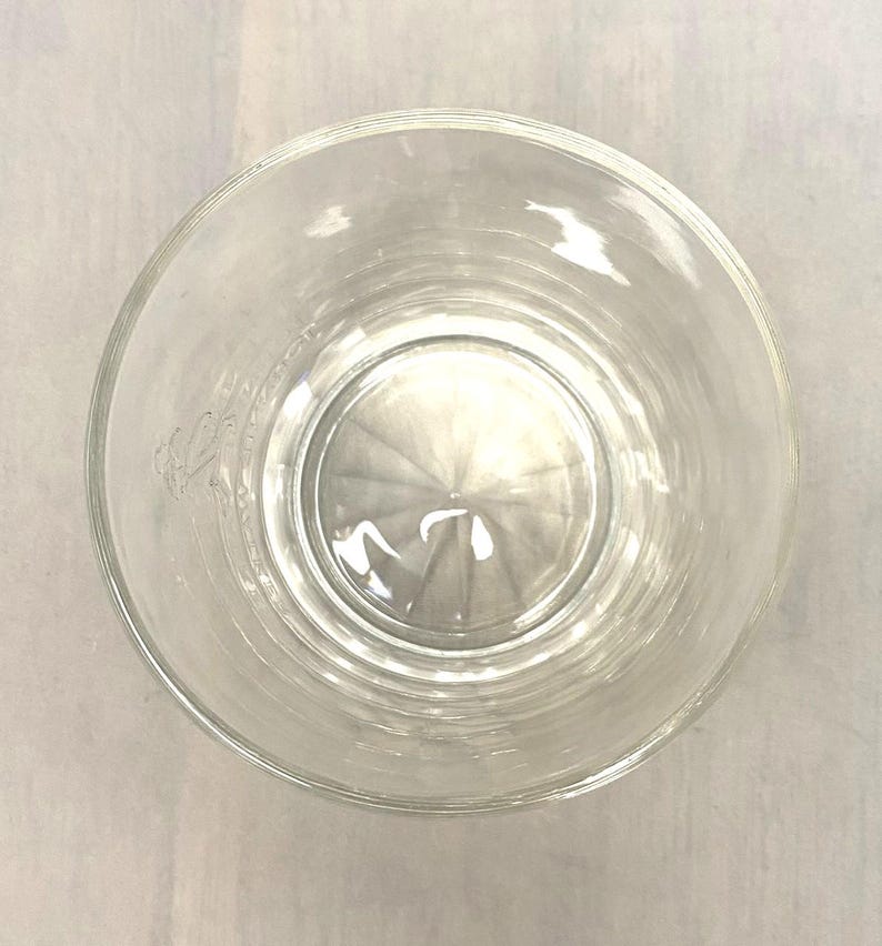 Puede incluir: Un vaso transparente y vac&iacute;o con un borde ancho, visto desde arriba. El vaso tiene una base interior ligeramente texturizada y un cuerpo liso y transparente. El vaso es probablemente para beber.