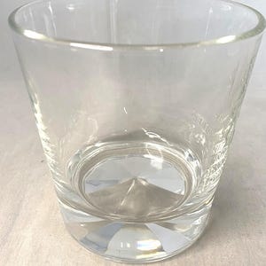 Puede incluir: Un vaso transparente y vac&iacute;o con una base gruesa facetada y un borde ligeramente ensanchado. El vaso tiene un dise&ntilde;o simple y elegante, adecuado para diversas bebidas. El vaso es de vidrio transparente.