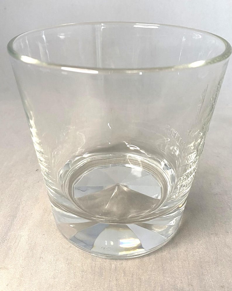 Puede incluir: Un vaso transparente y vac&iacute;o con una base gruesa facetada y un borde ligeramente ensanchado. El vaso tiene un dise&ntilde;o simple y elegante, adecuado para diversas bebidas. El vaso es de vidrio transparente.