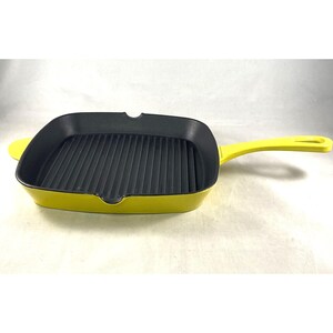 May include: A yellow cast iron grill pan with a black nonstick surface and a long handle.