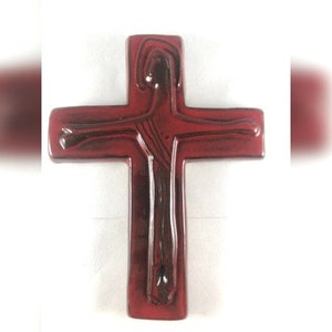 Może przedstawiać: Czerwony ceramiczny krzyż z wypukłym, fakturowanym wzorem ludzkiej postaci. Krzyż jest symbolem religijnym i stanowiłby doskonałe uzupełnienie kolekcji dekoracji domu.