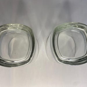 Puede incluir: Dos vasos de chupito de vidrio transparente con forma cuadrada.