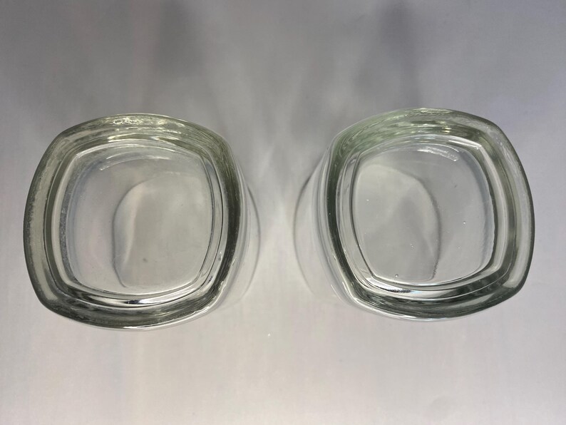 Puede incluir: Dos vasos de chupito de vidrio transparente con forma cuadrada.