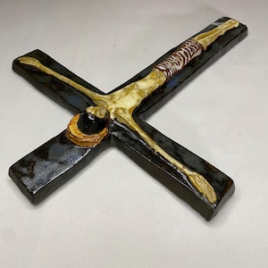 Może przedstawiać: Ceramiczny krucyfiks z ciemnoniebieską i brązową glazurą. Postać Jezusa przedstawiona jest w szkieletowej formie z koroną cierniową i przepaską lędźwiową.