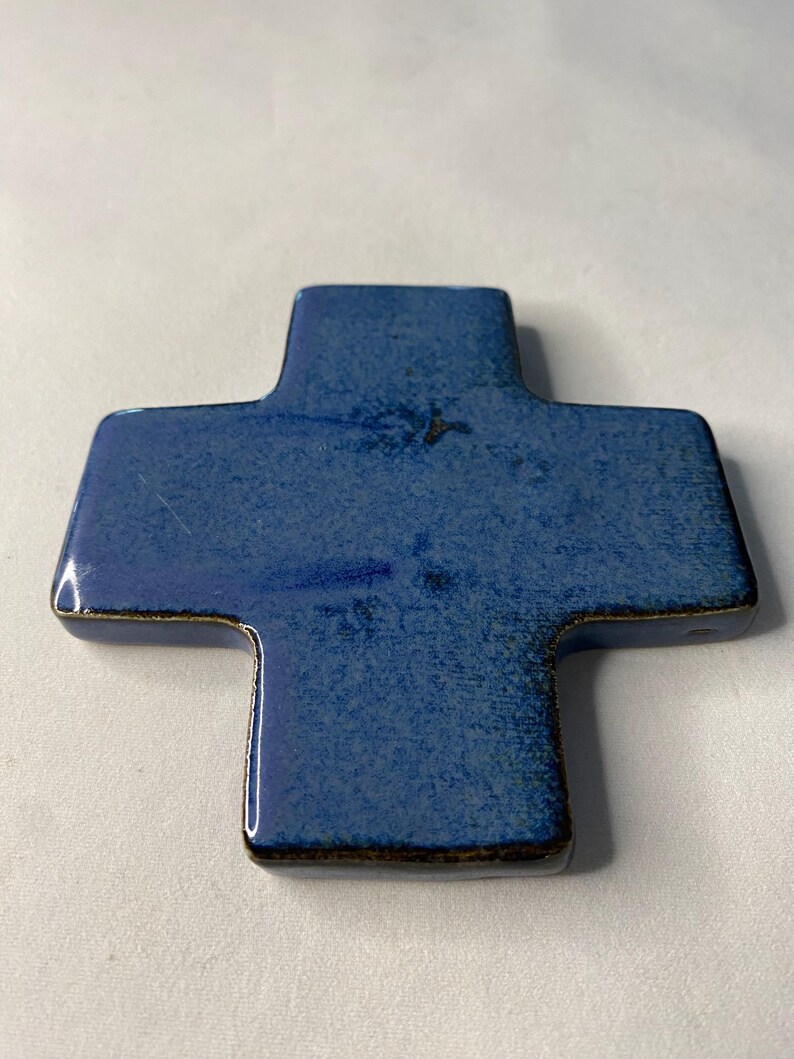 K&ouml;nnte beinhalten: Ein blaues Keramikkreuz mit leicht strukturierter Oberfl&auml;che. Das Kreuz hat einen dunkelblauen Rand.