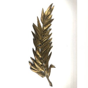 May include: A gold-colored metal leaf wall decor with a detailed design. The leaf is long and narrow with a pointed tip.