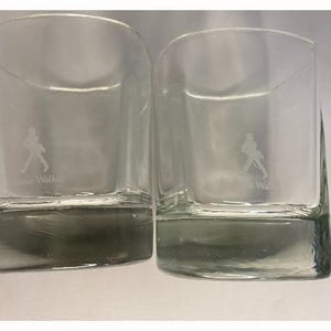Puede incluir: Dos vasos transparentes de vidrio con una figura caminando grabada en la parte delantera. El texto "Johnnie Walker" est&aacute; grabado en la parte inferior del vaso.