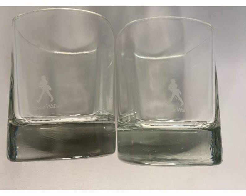 Puede incluir: Dos vasos transparentes de vidrio con una figura caminando grabada en la parte delantera. El texto "Johnnie Walker" est&aacute; grabado en la parte inferior del vaso.