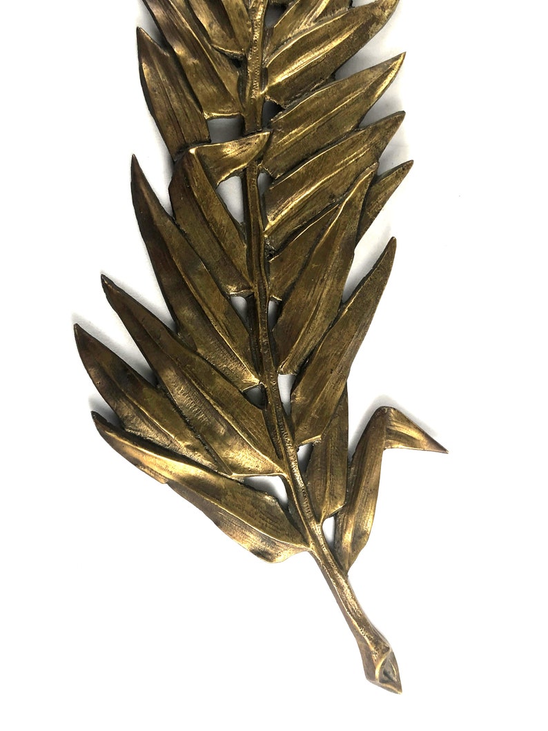 May include: A gold-colored metal leaf wall decor with a detailed design. The leaf is made of a single piece of metal and has a realistic appearance.