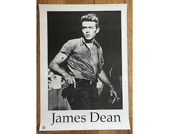 May include: Black and white photo of James Dean, a famous actor, wearing a button-down shirt and jeans. The photo is printed on a poster with the text "James Dean" at the bottom.