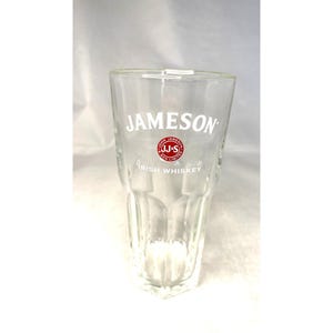 Può includere: Un bicchiere trasparente e alto di Jameson Irish Whiskey con un design sfaccettato. Il logo Jameson è stampato in bianco con un emblema circolare rosso e bianco. Le parole "Irish Whiskey" sono stampate sotto.