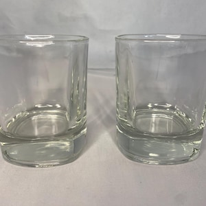 Puede incluir: Dos vasos transparentes de vidrio, cada uno con un fondo redondeado y lados rectos. Los vasos est&aacute;n vac&iacute;os y parecen estar hechos de vidrio grueso.