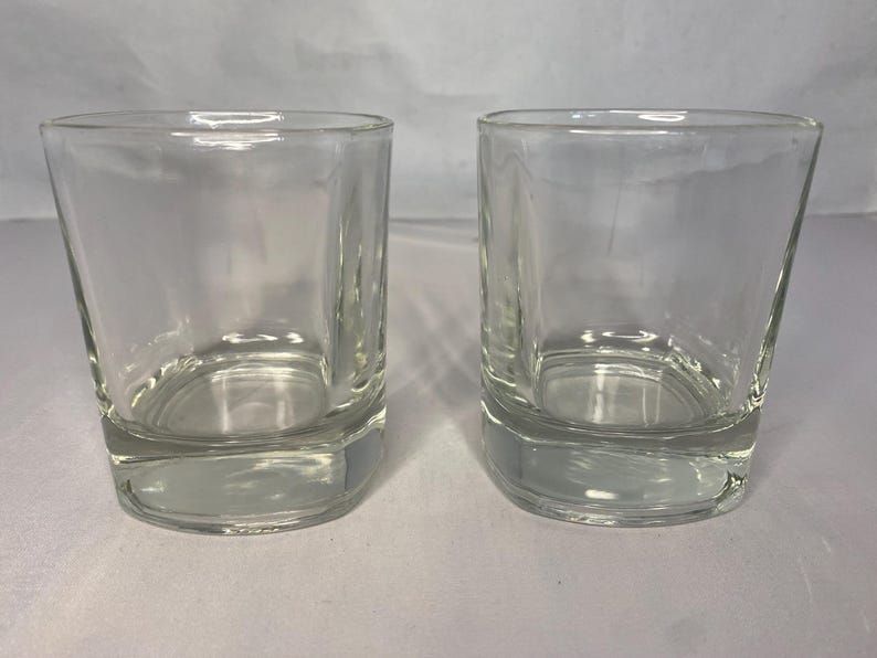 Puede incluir: Dos vasos transparentes de vidrio, cada uno con un fondo redondeado y lados rectos. Los vasos est&aacute;n vac&iacute;os y parecen estar hechos de vidrio grueso.