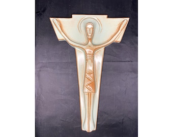 May include: A ceramic wall sculpture of a stylized figure of Jesus Christ on a cross. The sculpture is painted in shades of brown and green.