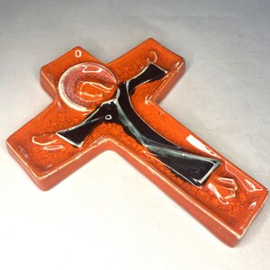 May include: Orange ceramic wall cross with a black and white figure of Jesus Christ.