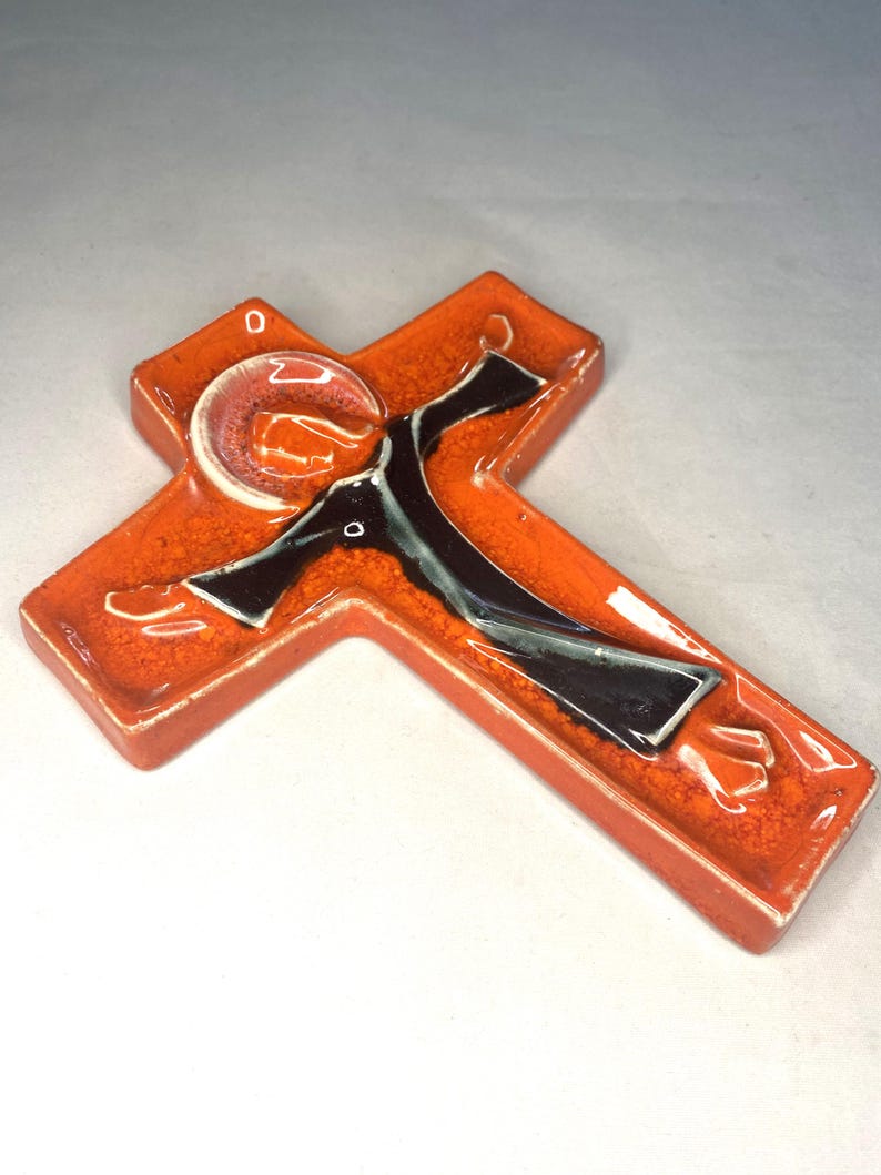 May include: Orange ceramic wall cross with a black and white figure of Jesus Christ.