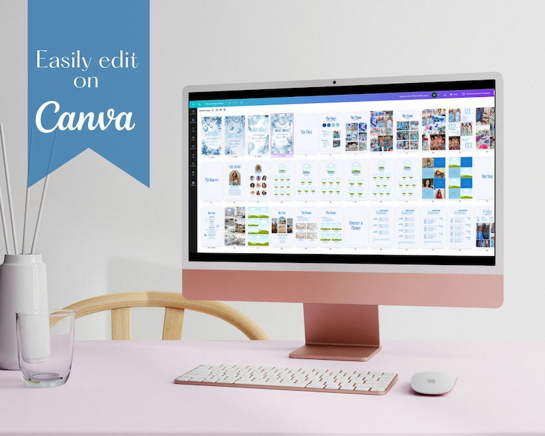 May include: A computer screen displaying a digital design template for a wedding scrapbook. The template is open in Canva, a graphic design platform. The screen is on a pink desk with a white keyboard and a white mouse.