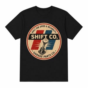 May include: A black t-shirt featuring a circular graphic with a vintage-style gear shifter illustration. The text reads "SHIFT CO." and "BUILT FOR SPEED & RELIABILITY" along with "GARAGE PARTS CO." over red and blue diagonal stripes.
