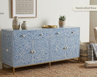 May include: A blue and white handcrafted bone inlay sideboard with a floral design. The cabinet has six drawers and two doors with silver hardware. The sideboard is on gold legs and has a gold tray on top. The text "Handcrafted Bone Inlay Sideboard" is visible.
