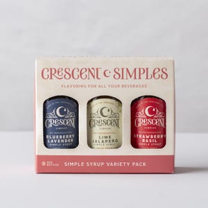 May include: A variety pack of Crescent Simples simple syrups in a decorative box. The box features three small bottles of flavored syrups: Blueberry Lavender, Lime Jalapeno, and Strawberry Basil. The packaging includes the text "Flavoring for all your beverages."