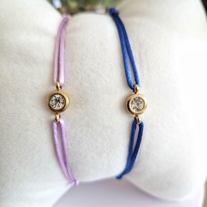 May include: Two adjustable bracelets with a single clear rhinestone on each. One bracelet is lavender and the other is blue.