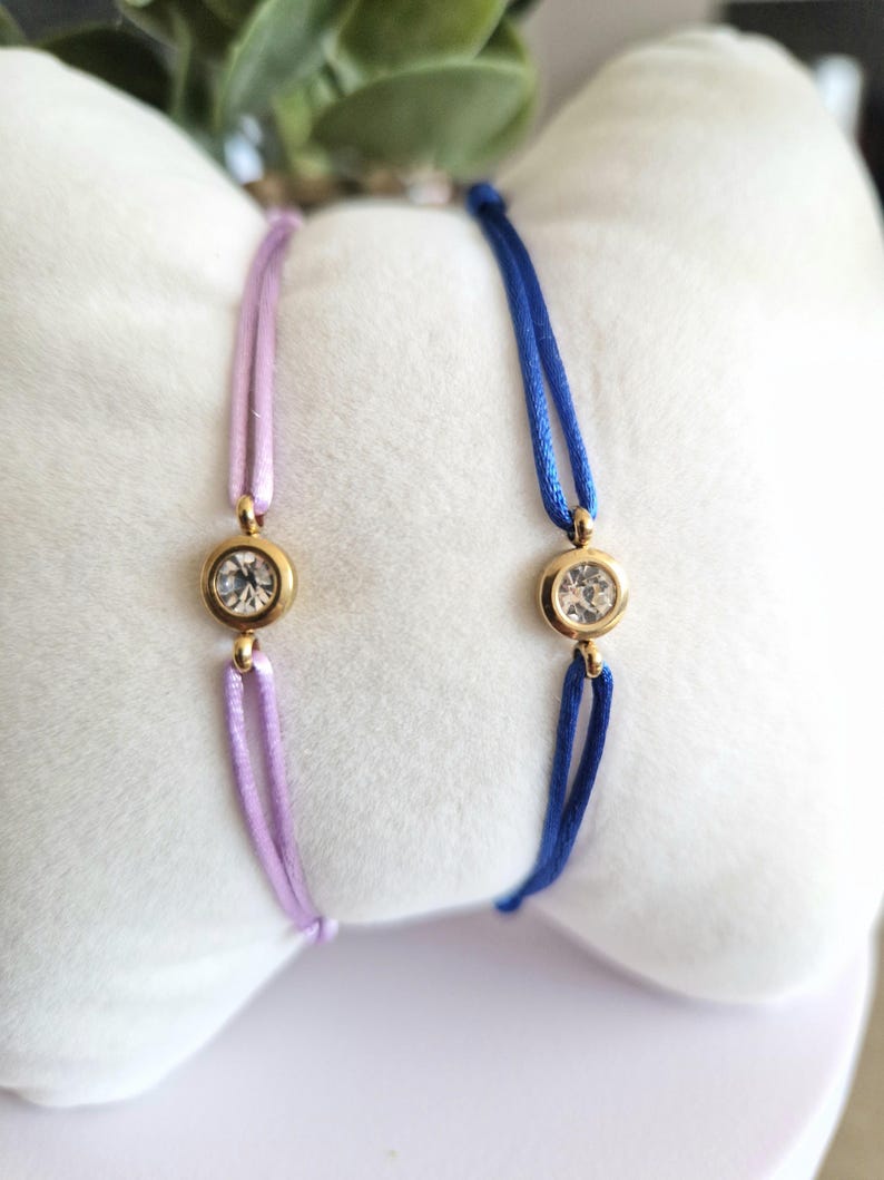 May include: Two adjustable bracelets with a single clear rhinestone on each. One bracelet is lavender and the other is blue.