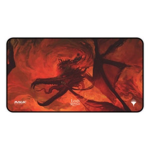 Può includere: Un tappetino da gioco rosso e arancione con un drago su uno sfondo infuocato. Il tappetino da gioco ha il testo "Magic: The Gathering" e "Il Signore degli Anelli" stampato su di esso.