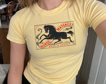 May include: A yellow t-shirt with a black and red graphic of a horse and the text "Horse Matches Made in Sweden."