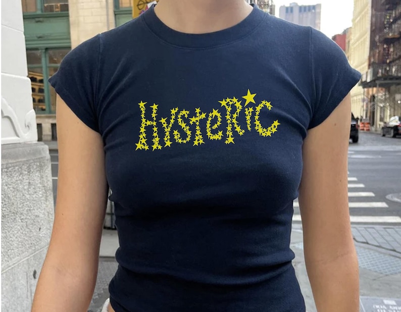 May include: A navy blue t-shirt with a yellow star design spelling out the word "HYSTERIC".