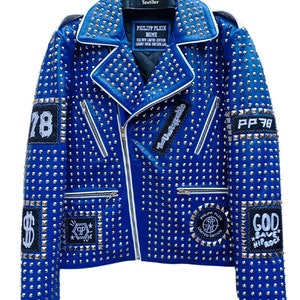 May include: A blue leather jacket with silver studs and various patches. The patches include the text "The Unstoppable", "PP 78", "God Save Hip Rock", and "Philipp Plein Home Limited Edition".