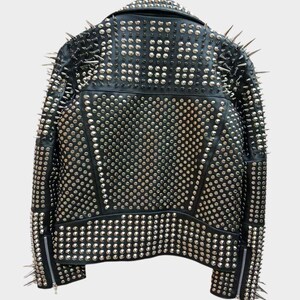 May include: Black leather jacket covered in silver studs and spikes. The back of the jacket is visible, showcasing the extensive studding and spiked accents on the shoulders and collar. The jacket has a classic biker style with a zipper closure.