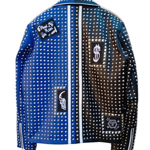 May include: A blue and black leather jacket with silver studs and patches. The jacket has a white stripe down the center back and features patches with the text "Punk is Plan" and a dollar sign.