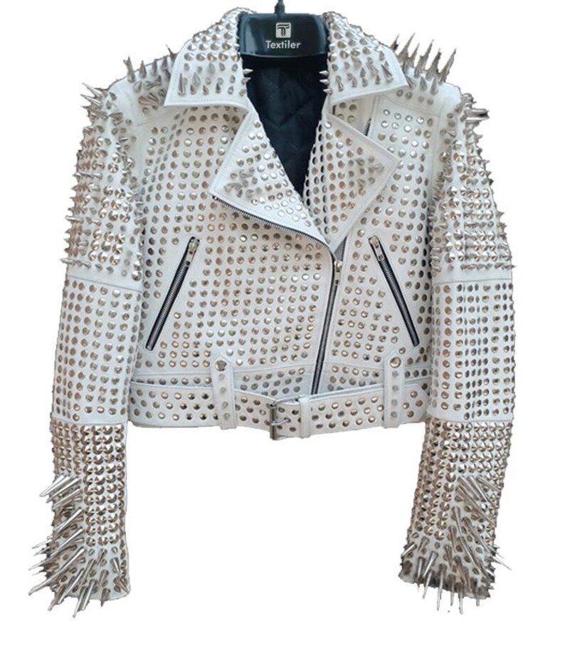 May include: White leather jacket with silver metal studs and spikes. The jacket features a notched collar, a zipper closure, and multiple pockets. The sleeves and shoulders are heavily embellished with studs and spikes, creating a bold, edgy look.