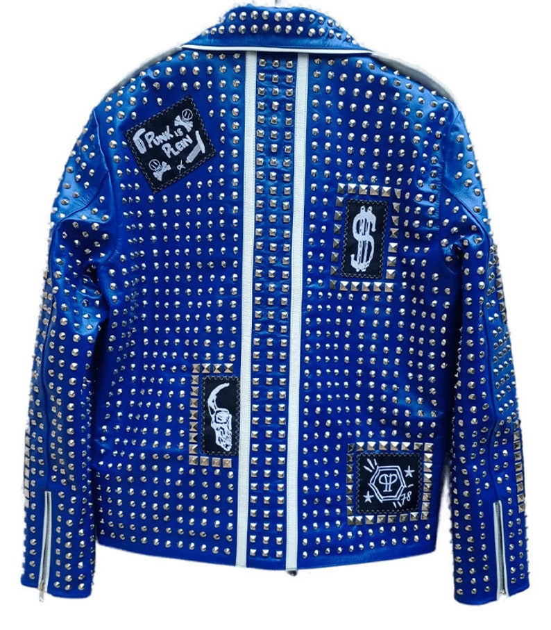 May include: A blue leather jacket with silver studs and patches. The patches include a skull, a dollar sign, and the text "Punk is Plain".