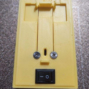 May include: A yellow 3D printed box with a black toggle switch and two screws. The box has the word "tardy" printed on the top.