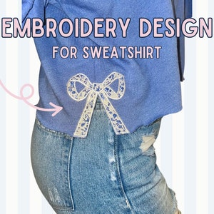 May include: A blue sweatshirt with a white bow embroidered on the back. The text "EMBROIDERY DESIGN FOR SWEATSHIRT" is written above the bow.