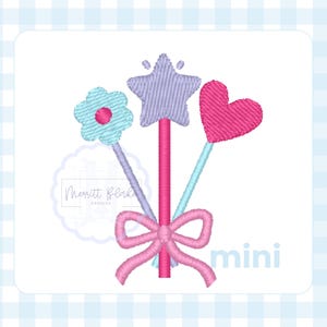 May include: An embroidered design featuring three wands with a flower, star, and heart, tied together with a pink bow. The wands are in shades of blue, purple, and pink. The word "mini" is also included.