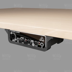 Könnte beinhalten: Ein schwarzes Behringer U-Phoria UMC22 Audio-Interface mit Knöpfen und Reglern, montiert unter einem hellen Holztisch.