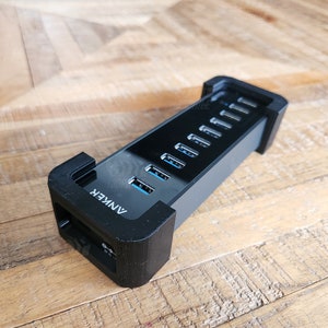 May include: A black Anker USB hub with seven ports. The hub is designed to stand upright and has a black plastic base.