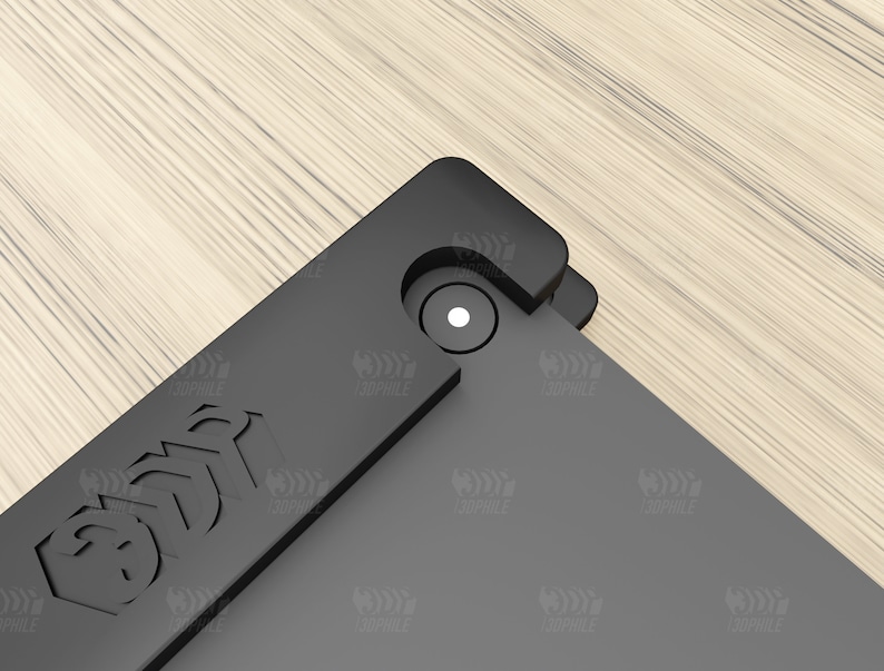 Puede incluir: Primer plano de una funda de tel&eacute;fono negra con un peque&ntilde;o c&iacute;rculo blanco en el centro. La funda tiene un borde elevado alrededor del objetivo de la c&aacute;mara y una superficie texturizada.