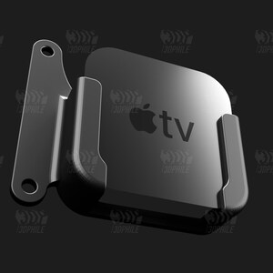 May include: A black metal wall mount for an Apple TV streaming device. The mount has a simple design with two arms that hold the device securely in place. The Apple TV is visible in the mount, with the Apple logo and the text "tv" displayed on the front.