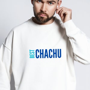 以下が含まれることがあります： 前面に「BEST CHACHU」と書かれた青と水色のグラフィックが施された白いスウェットシャツです。