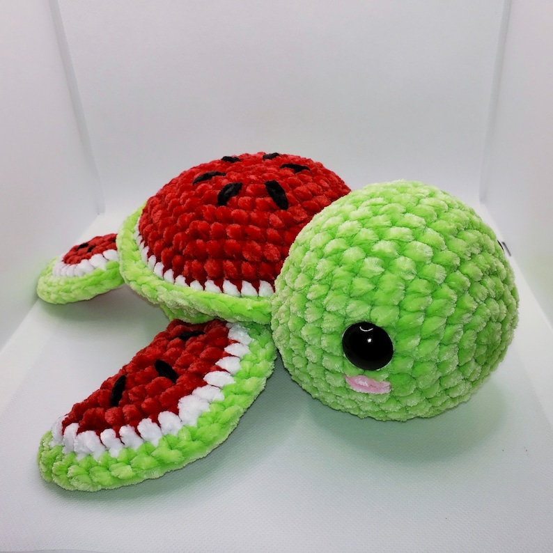 May include: A crocheted watermelon turtle plush toy with a green shell and red and white watermelon patterned body.