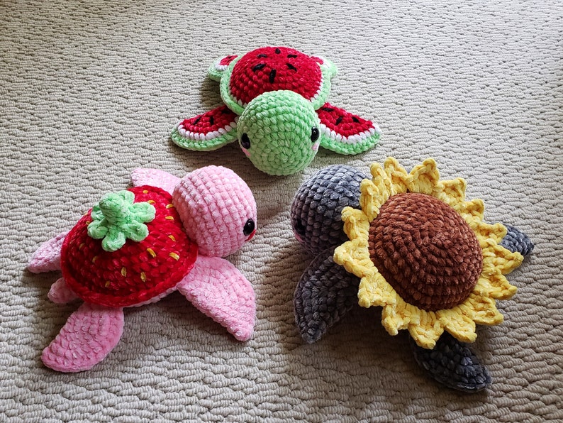 May include: Three crocheted turtle toys. One is pink with a strawberry on its back, one is green with a watermelon on its back, and one is gray with a sunflower on its back.