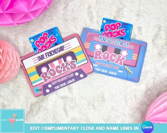 Puede incluir: Dos tarjetas en forma de casete rosa y azul con el texto "Pop Rocks" y "You So Totally Rock". Las tarjetas están decoradas con corazones y estrellas. El texto "Happy Valentine's Day" y "Our Friendship Rocks" también están incluidos en las tarjetas.