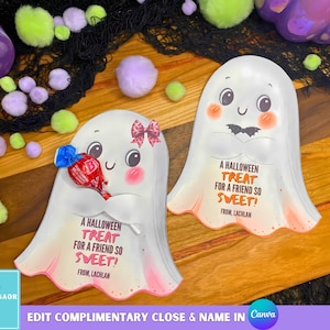 Puede incluir: Dos portadores de golosinas de Halloween con forma de fantasma blanco con el texto "A Halloween Treat For A Friend So Sweet!" y "From, Lachlan." Un fantasma sostiene una piruleta envuelta. Las mejillas rosas y los lazos decoran los fantasmas.