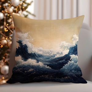 May include: A decorative throw pillow with a blue and white wave pattern on a beige background. The pillow is sitting on a light gray couch.
